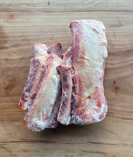 Frozen Carrell Farms water buffalo rib bones for pets on a wooden cutting board