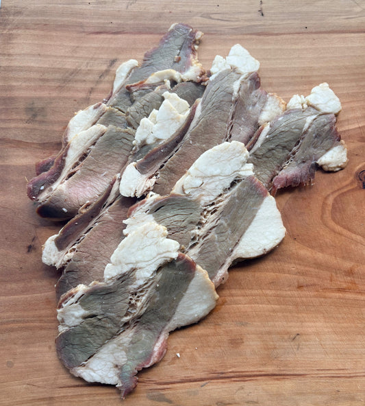 Sliced Carrell Farms water buffalo brisket bacon on a wooden cutting board