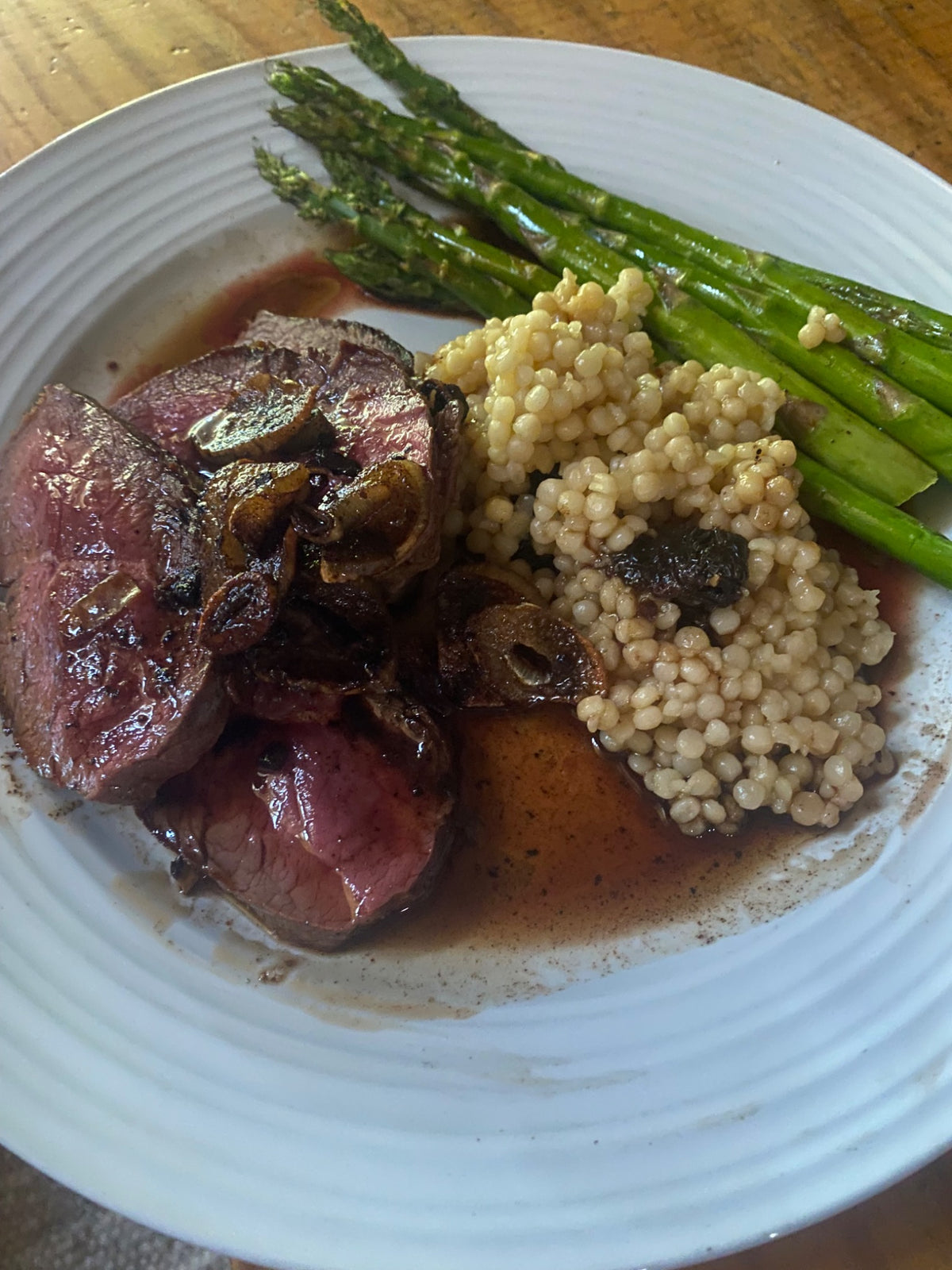 Sliced Carrell Farms water buffalo heart served with mushrooms, couscous, and asparagus